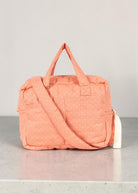 Playroom Collective Konges Sloejd doll diaper bag in coral cotton with white dots, featuring handles and strap.