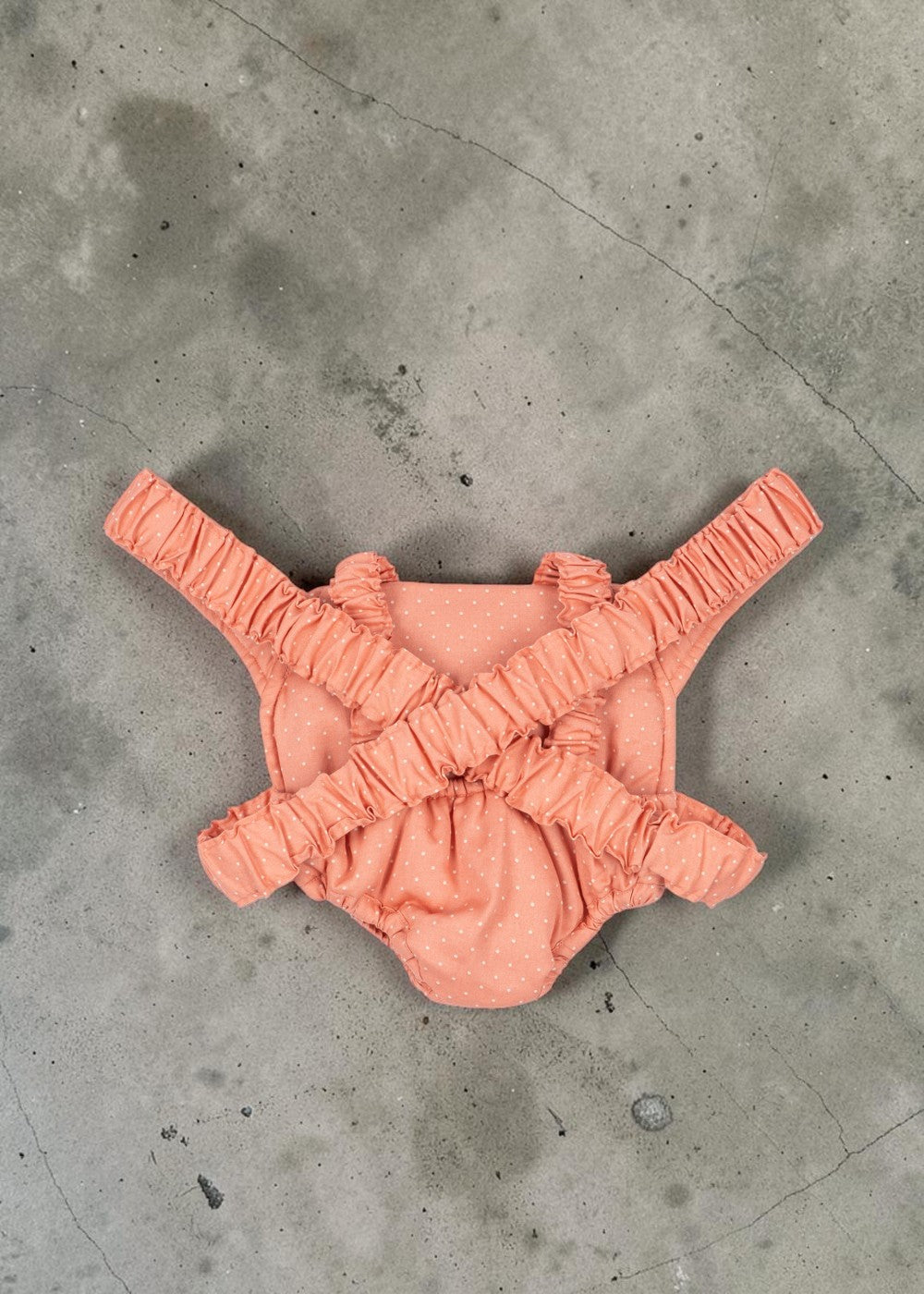 Playroom Collective Konges Sloejd doll carrier in rose coral cotton with white dots and flexible elastic straps.