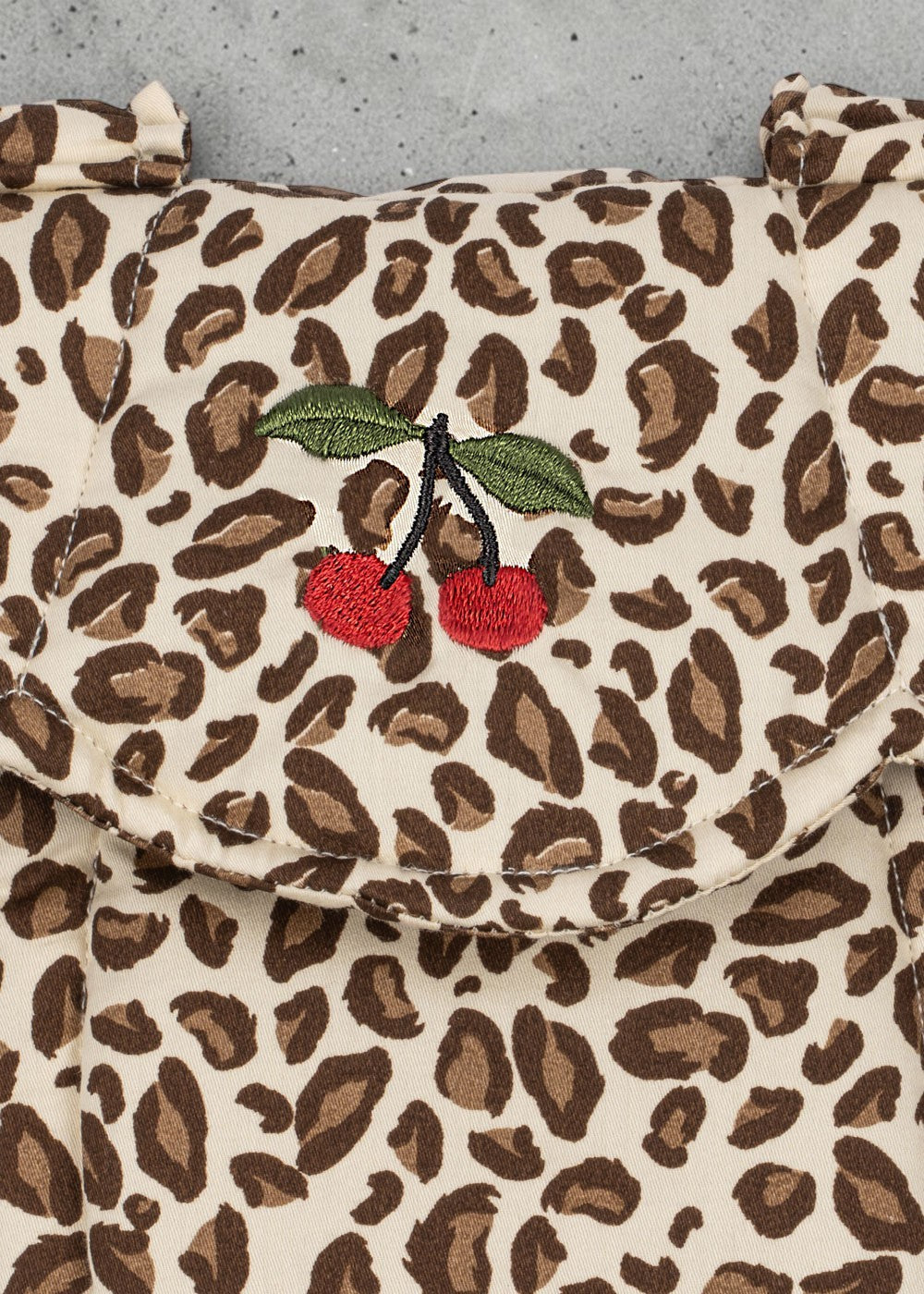 Playroom Collective Konges Sloejd baby doll carrier in cream and brown leopard print with embroidered cherry detail.