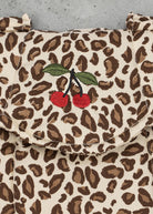 Playroom Collective Konges Sloejd baby doll carrier in cream and brown leopard print with embroidered cherry detail.