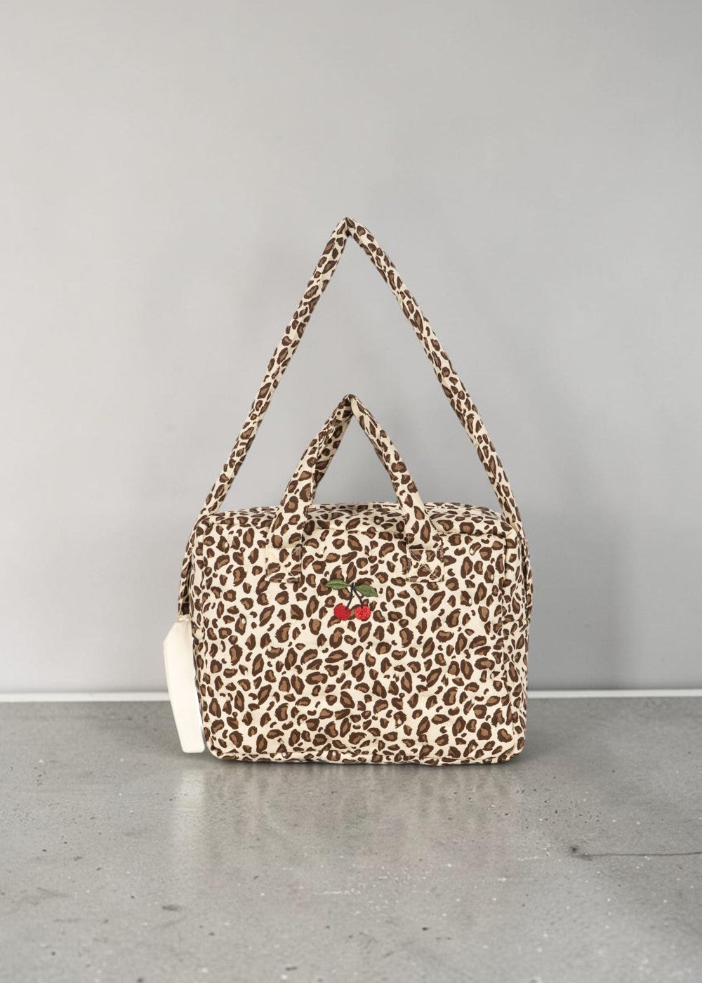 Playroom Collective Konges Sloejd leopard print cotton doll diaper bag with embroidered cherry detail and straps.