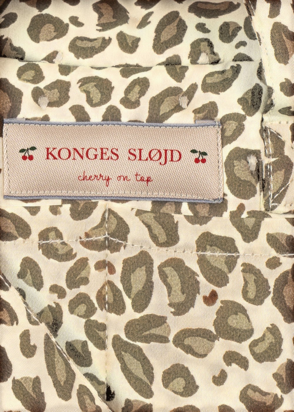 Playroom Collective Konges Sloejd doll diaper bag in cream and brown leopard print with cherry logo label