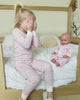 Girl and doll playing in pink pajamas