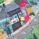 Children's puzzle with illustrated street scene featuring a store and characters.
